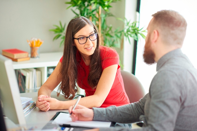 Twee professionals in gesprek met elkaar aan een bureau